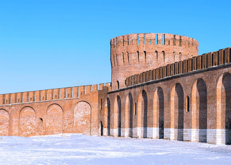 Brick round big tower high with a crenellated wall with arches protective wall of the Kremlin against a blue winter sky. Smolensk