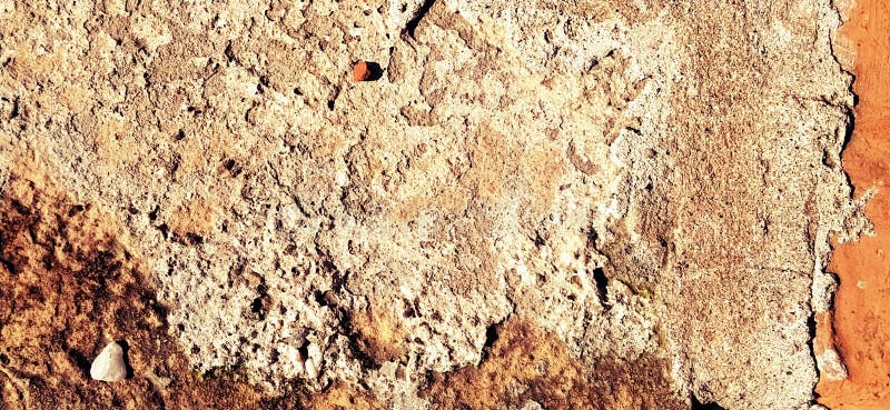 Brick or stone close-up. Texture or background. Bright red, brown, orange, beige colors. Dust, small pebbles, sand, soil and moss