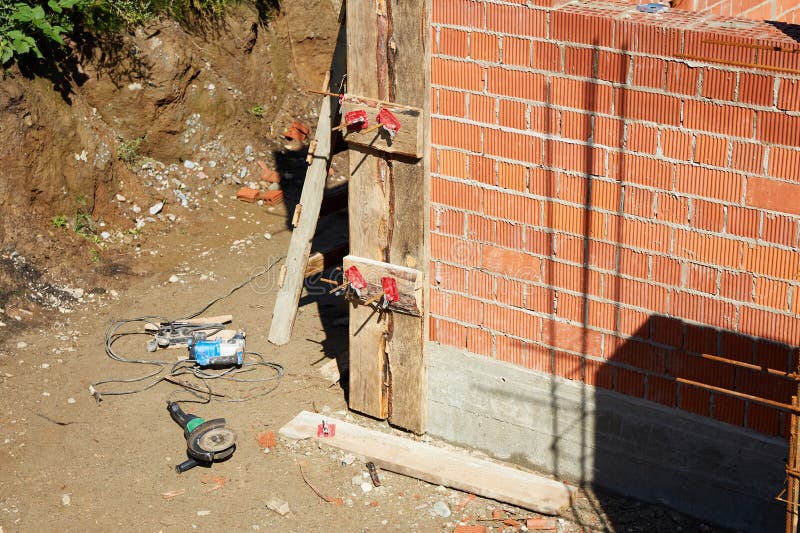 Brick wall assembly is in progress with clamps securing the structure. stock photos