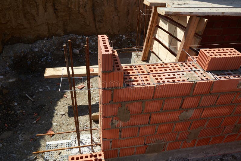 Brick wall construction in progress at a building site during daylight hours stock image