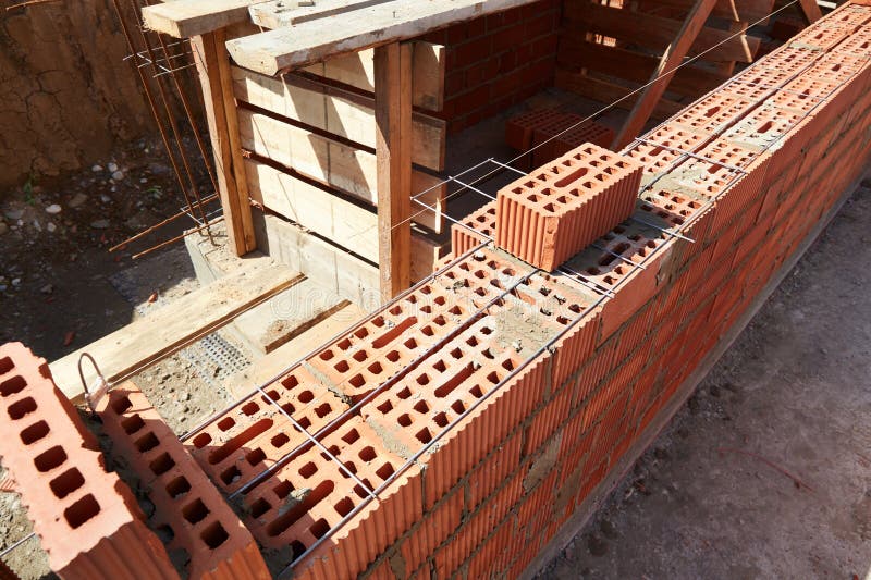 Brick wall construction in progress at a building site during daylight hours stock images