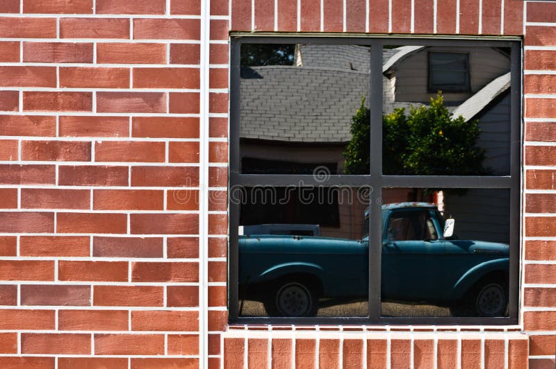 Brick wall with window and reflection of truck