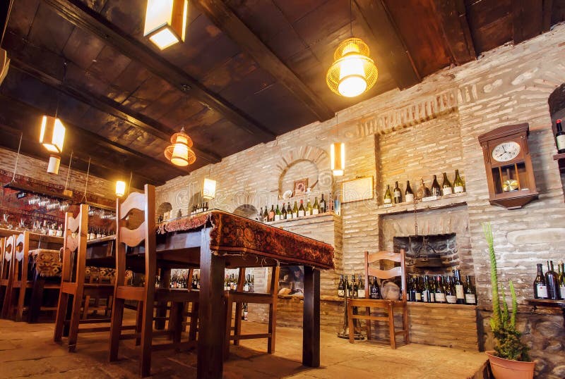 Brick walls of old restaurant with wine bottles on shelves, wooden tables and bright lamps royalty free stock photo Brick walls of old restaurant with wine bottles on shelves, wooden tables and bright lamps royalty free stock photo