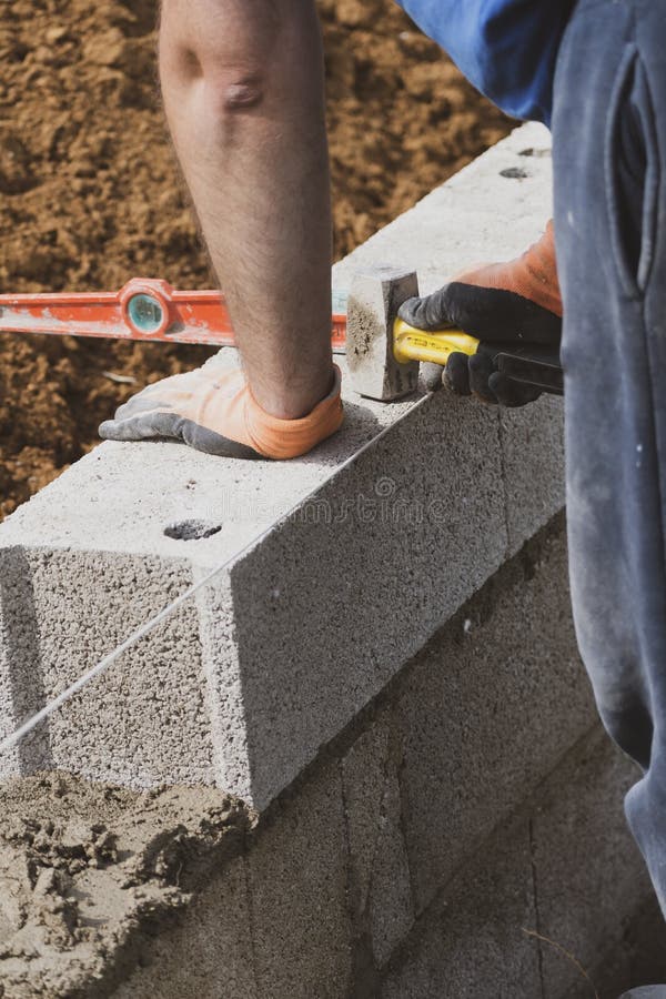 Bricklayer Spreading Concrete with a Trowel and Level To Build a Wall at a Construction Site