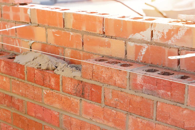 Bricklayer Laying Bricks on Mortar on New Residential House