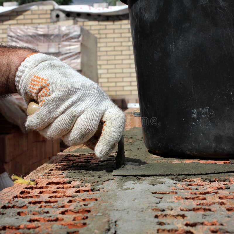 Bricklayers hands with in masonry trowel bricklaying new house wall on foundation. Close up of industrial bricklayer installing stock photography Bricklayers hands with in masonry trowel bricklaying new house wall on foundation. Close up of industrial bricklayer installing stock photography