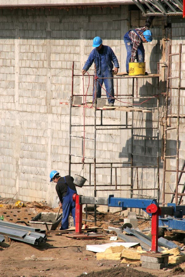 Albaniles en cascos sobre el andamio.