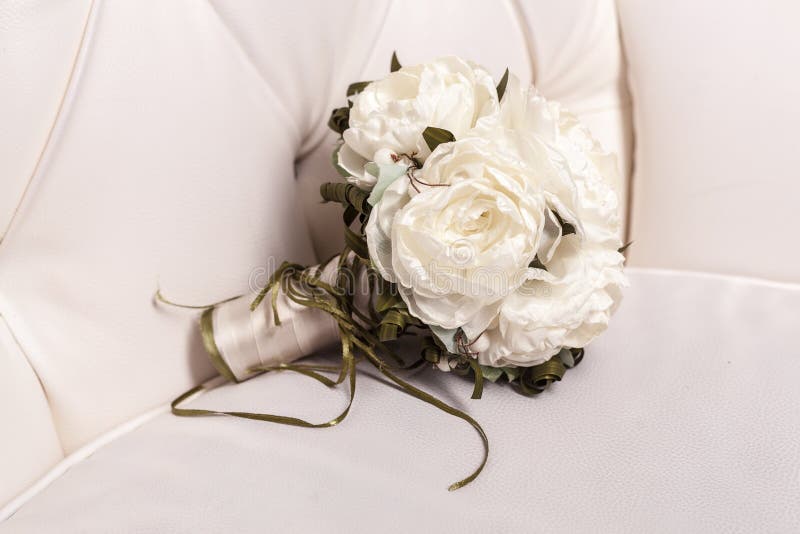 Bridal bouquet of white rose in bright colors on white leather b