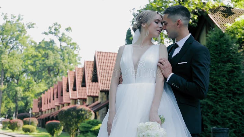 Bridal omhelst bride en groom deelt een aangenaam moment buiten met griekenland en bouwachtergrond.