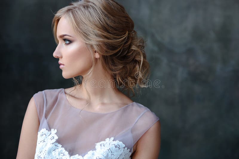 Bride blonde woman in a modern color wedding dress with elegant hair style and make up. Fashion beauty portrait over textured background