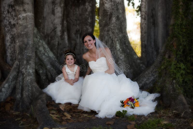 Bride and flower girl under tree