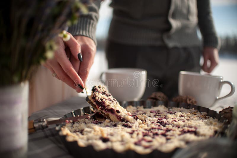 The bride and groom cut the wedding cake in tin metal plate outdoors in the winter on the coast of the frozen river