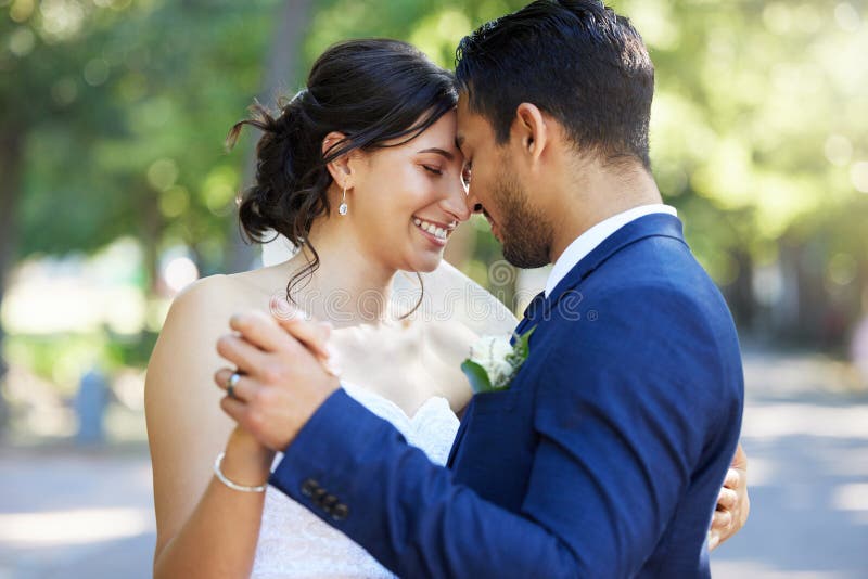 Bride and groom dancing outside. Mixed race newlyweds enjoying romantic moments on their wedding day. Happy young