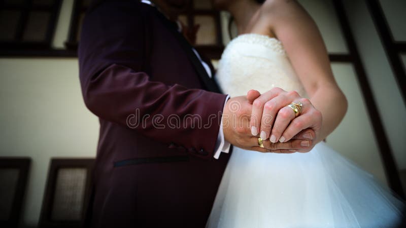 Bride and groom holding hands with engagement rings on their fingers close up view wedding shoot concept