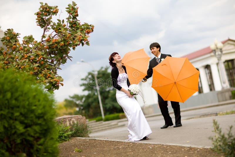Bride and groom with orange umbrellas