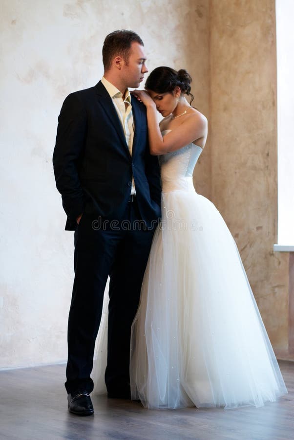 Bride and groom standing in empty room