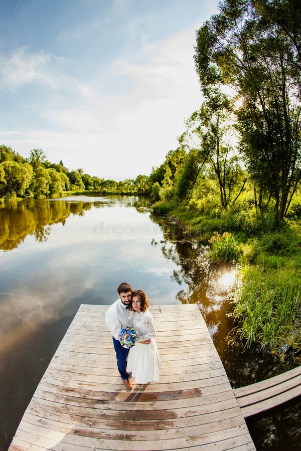 The bride and groom are standing on a wooden pier near the pond royalty free stock images The bride and groom are standing on a wooden pier near the pond royalty free stock images