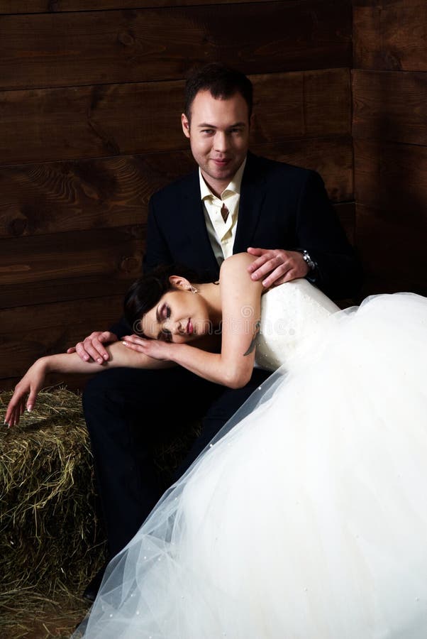 Bride lying on groom s lap in barn
