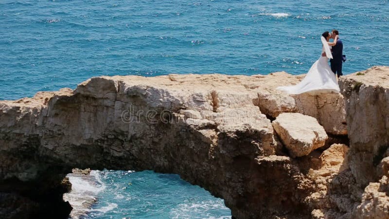 Bride on a stone bridge in the sea kissing