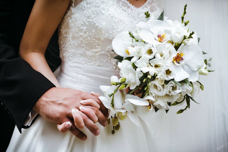 Bride with wedding bouquet of white orchids and groom holding ea stock photography Bride with wedding bouquet of white orchids and groom holding ea stock photography