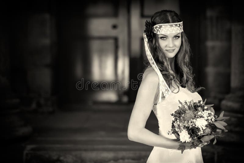 Bride with wedding flowers bouquet in white dress with wedding hairstyle and makeup. Smiling woman in wedding dress waiting for gr