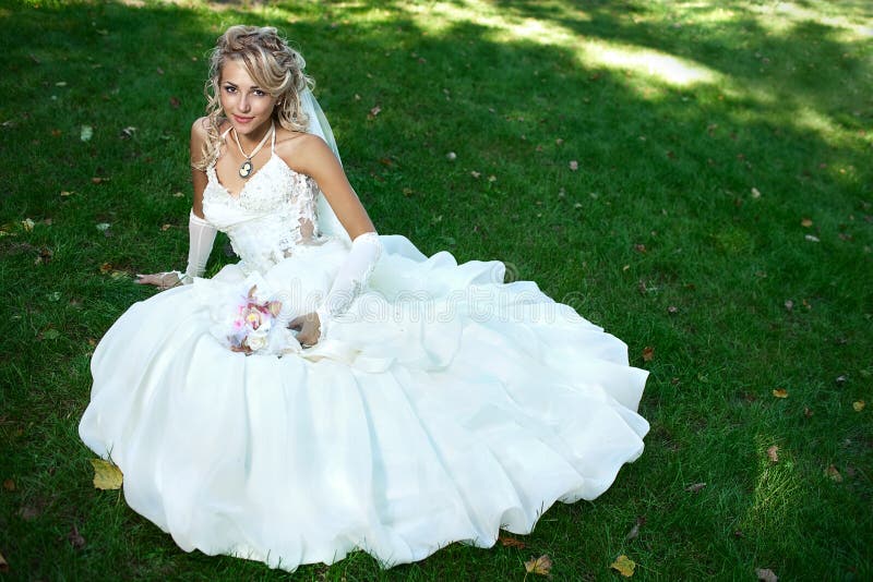 Bride in white dress on green grass