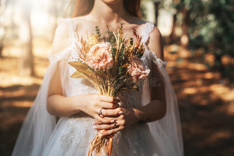 Bride with white wedding dress in forest holding colorful and dried wedding bouquet. royalty free stock photos Bride with white wedding dress in forest holding colorful and dried wedding bouquet. royalty free stock photos