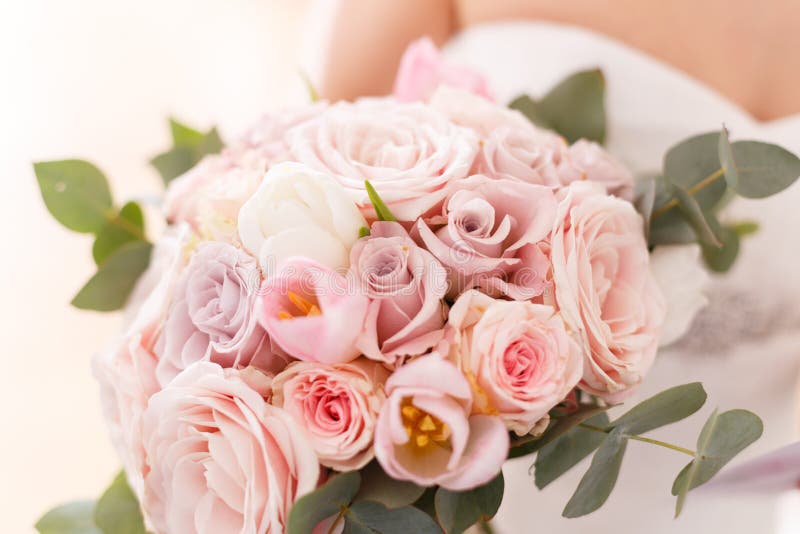 Brides bouquet of roses, tulips and eucalyptus, in her hands