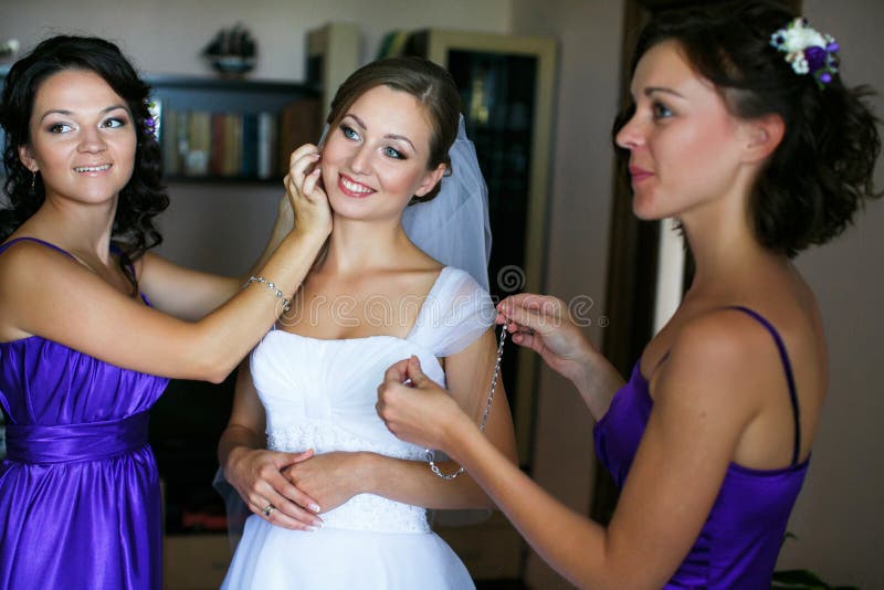 Bridesmaids помогают невесте положить дальше серьги и ожерелье стоковое изображение Bridesmaids помогают невесте положить дальше серьги и ожерелье стоковое изображение