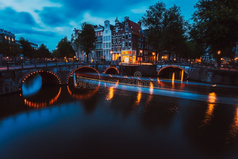 Bridge illumination and boat light trails in evening Amsterdam with reflection in Herengracht canal. Typical dutch royalty free stock images Bridge illumination and boat light trails in evening Amsterdam with reflection in Herengracht canal. Typical dutch royalty free stock images