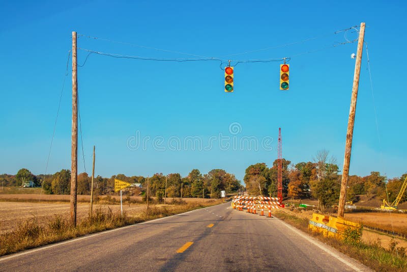 Bridge repair with one lane open and temporary traffic lights in rural Indiana on a late autumn morning with crane and other