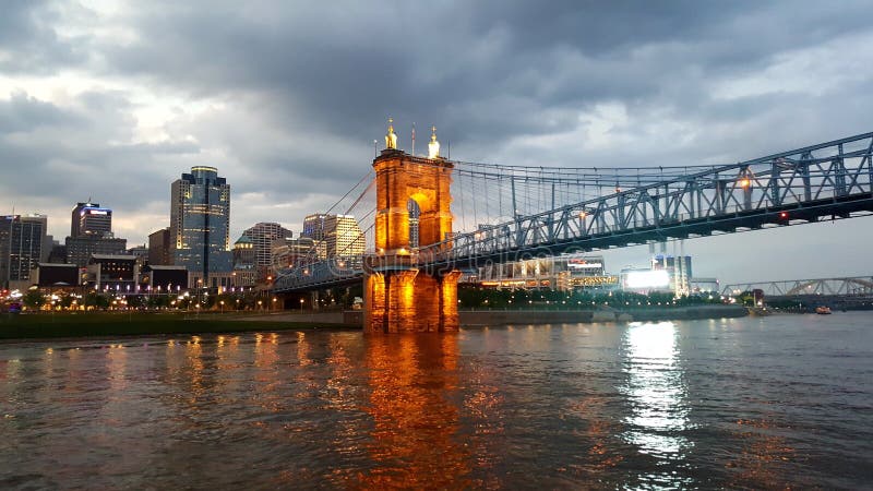 City of Cincinnati, Ohio in the background with the bridge coming into it light up at dusk and reflected on the Ohio river. City of Cincinnati, Ohio in the background with the bridge coming into it light up at dusk and reflected on the Ohio river