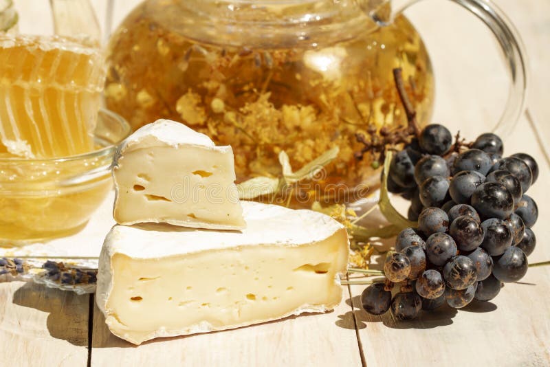 Brie type of cheese. Camembert cheese. Close up. Fresh Brie cheese and a slice on a wooden white table with honey, black stock photos Brie type of cheese. Camembert cheese. Close up. Fresh Brie cheese and a slice on a wooden white table with honey, black stock photos