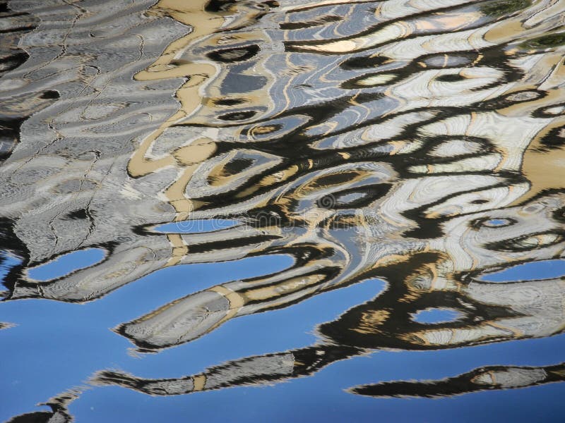 Bright abstract reflection of building in blue water.