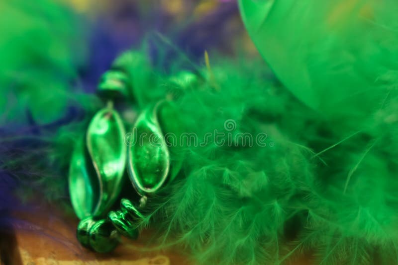 Colorful green and purple blurred Mardi Gras background with feathers and beads