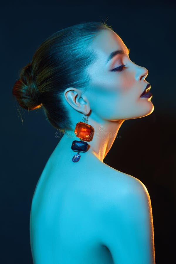 Bright contrasting beauty makeup portrait of a woman in blue and red shadow tones. Perfect clean skin and face makeup, dark royalty free stock image Bright contrasting beauty makeup portrait of a woman in blue and red shadow tones. Perfect clean skin and face makeup, dark royalty free stock image