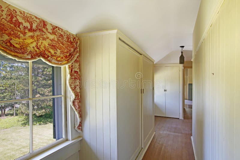 Bright Empty Hallway With Hardwood Floor And Vaulted Ceiling