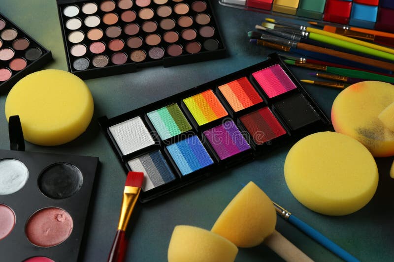 Bright face paints, brushes and sponges on color background stock image
