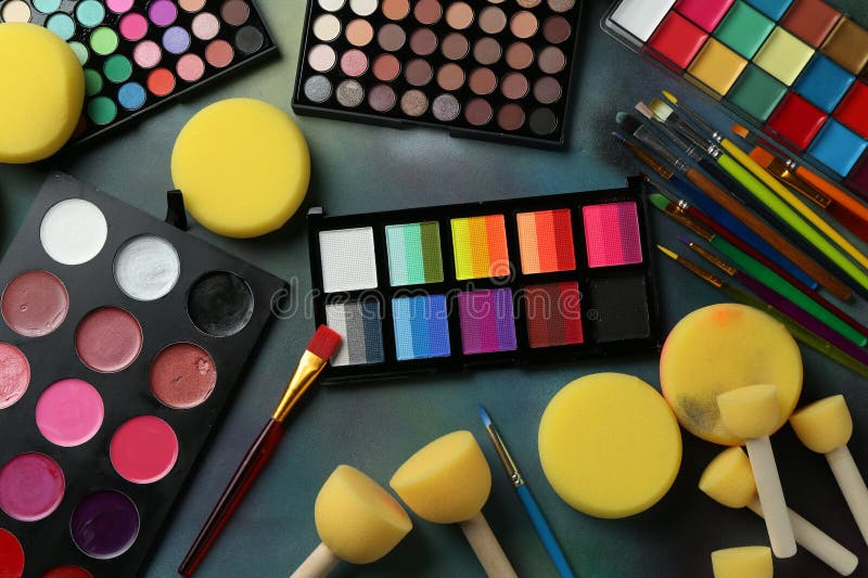 Bright face paints, brushes and sponges on color background, flat lay royalty free stock image