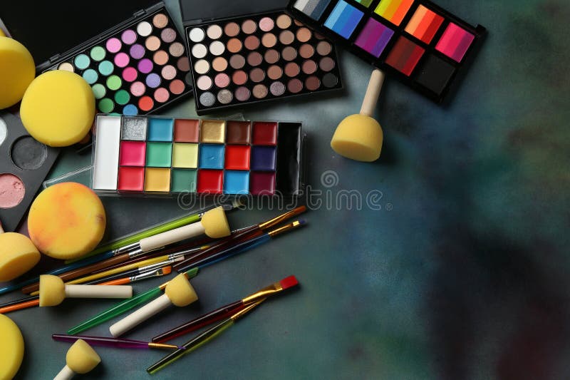 Bright face paints, brushes and sponges on color background, flat lay. Space for text stock photos