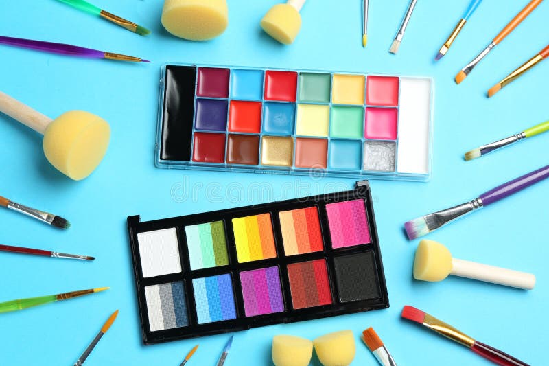 Bright face paints, brushes and sponges on light blue background, flat lay royalty free stock photos