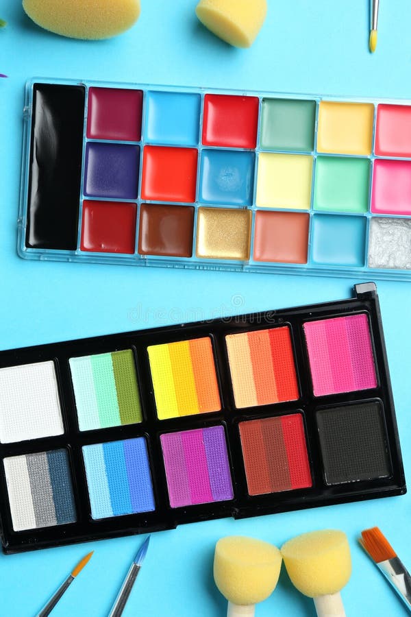 Bright face paints, brushes and sponges on light blue background, flat lay royalty free stock image