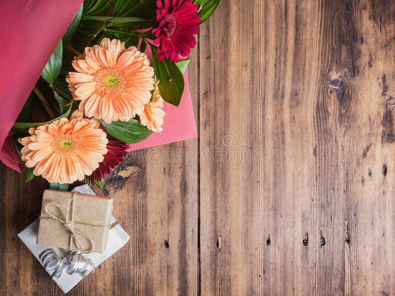 Bright flowers on old wooden background, top view. Bouquet of flowers with gift boxes. Decoration made of chrysanthemums, daisies decorative plants for birthday card. Selective soft focus