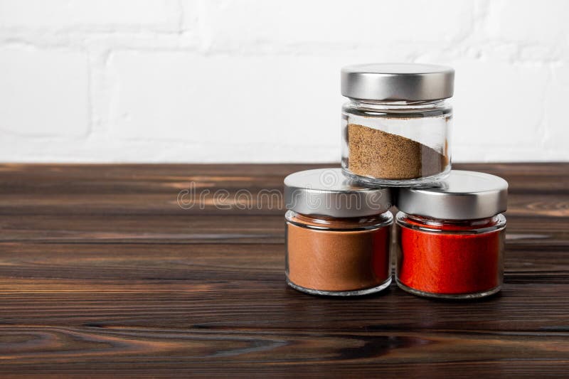 Bright Fragrant Spices in Glass Jars of Different Sizes on a Wooden