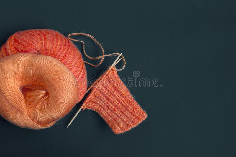 Bright knitting orange colorful melange mohair scarf, yarn ball and knitting needles. The beginning of comfort knit cloth, creativ