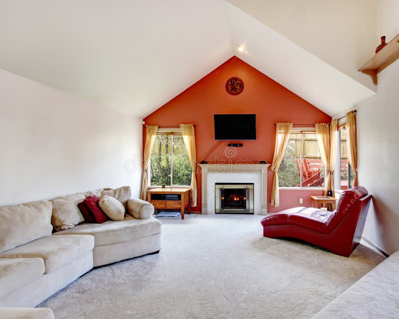 Bright living room with white and orange wall, vauled ceiling, beige carpet floor. Fireplace with red armless chair and beige couch make it cozy and comfortable. Bright living room with white and orange wall, vauled ceiling, beige carpet floor. Fireplace with red armless chair and beige couch make it cozy and comfortable