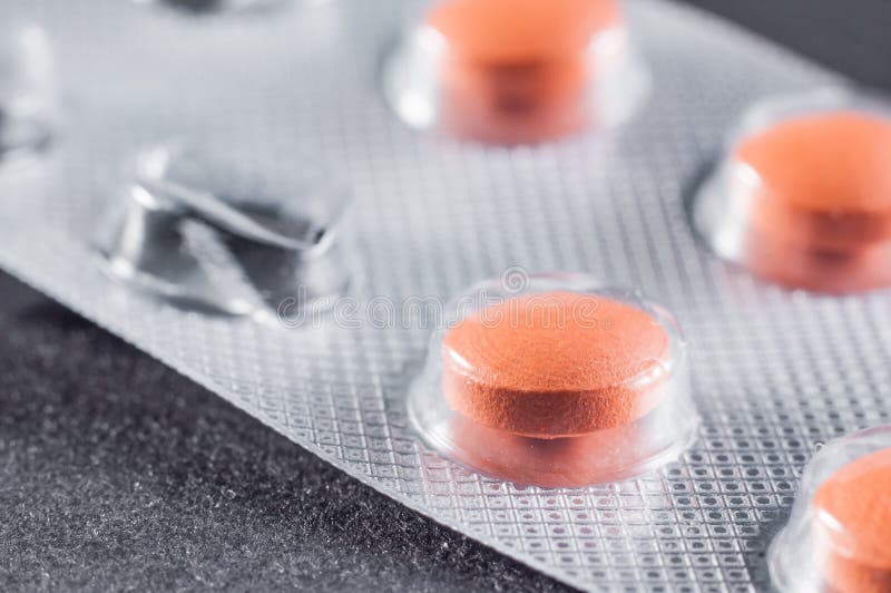 Bright Orange Pills in Sticks with One Empty Cell Used, Closeup Stock