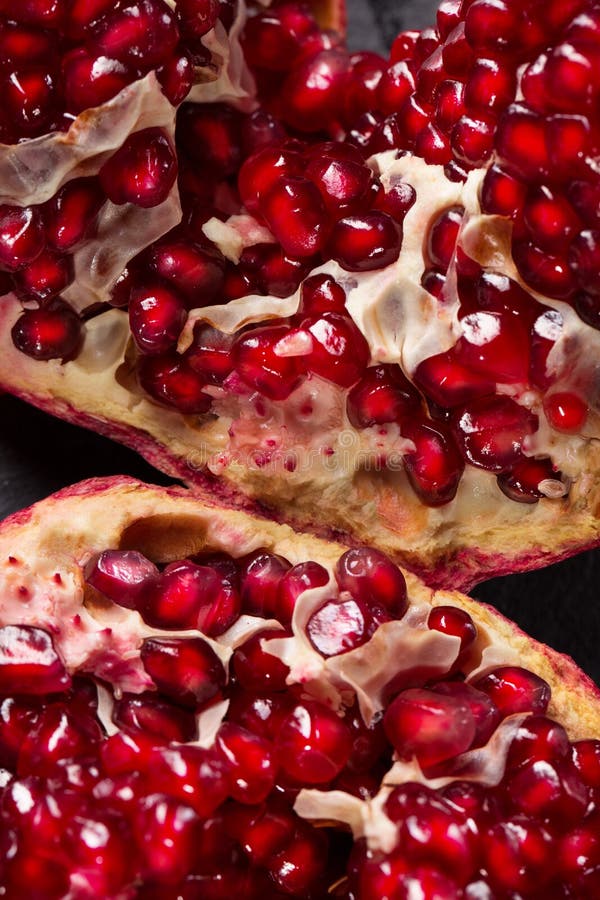 Bright red pomegranate broke down into parts on a black background. Natural, fresh garnet for desserts and beverages. royalty free stock photography Bright red pomegranate broke down into parts on a black background. Natural, fresh garnet for desserts and beverages. royalty free stock photography