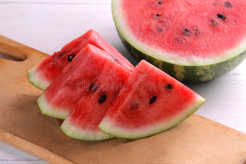 ripe slices of watermelon on a cutting board with a big and juicy watermelon on a white wooden background royalty free stock photos ripe slices of watermelon on a cutting board with a big and juicy watermelon on a white wooden background royalty free stock photos
