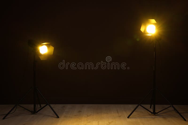 Bright Spotlights Near Wall in Dark Room, Space for Text Stock Image